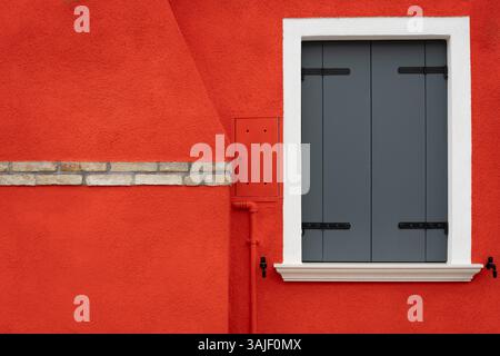 Burano-Fenster mit grauen Fensterläden an der Roten Wand Stockfoto
