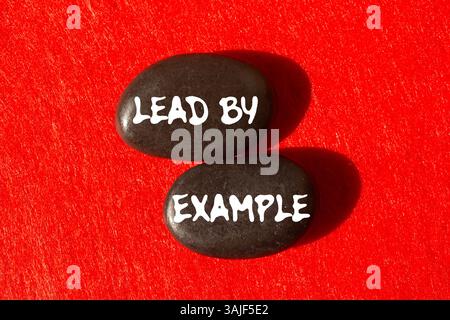 Beispiel-Meldung auf schwarzen Steinen auf rotem Hintergrund. Konzeptuelle Führung durch Beispielsymbol. Kopierbereich. Stockfoto
