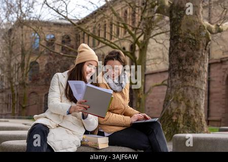 Zwei Studentinnen studieren gemeinsam im Universitätspark. Teamwork-Konzept mit zwei glücklichen Schülern, die im Park lernen Stockfoto