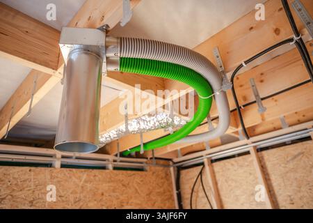 In einem neu errichteten Haus wird eine Lüftungsanlage installiert. Die Abbildung zeigt farbenfrohe Kanäle, die an den Deckenbalken angebracht sind, was das Programm angibt Stockfoto