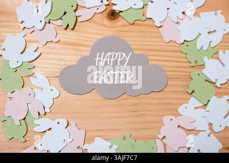 Holzrahmen mit einer Wolke und einem Haufen Osterhasen. Die Wolke ist weiß geschrieben und die Kaninchen sind in verschiedenen Farben Stockfoto