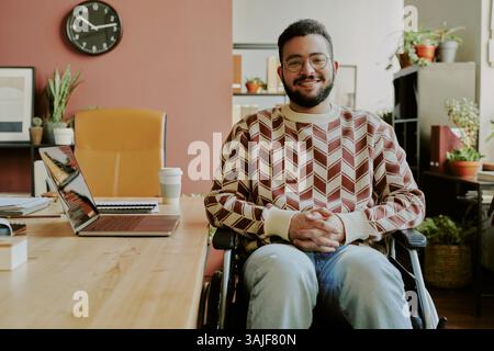 Mittleres Porträt eines gutaussehenden bärtigen Seniorentwicklers mit Behinderung, der in einem gemütlichen, geräumigen Büro für Fotos posiert Stockfoto