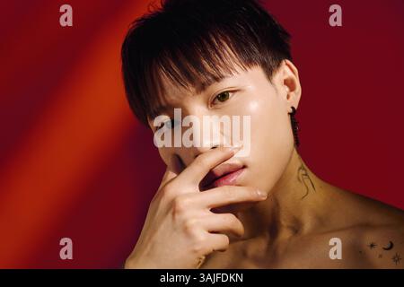 Ein selbstbewusster junger asiatischer Mann zeigt seinen einzigartigen Stil und Charme in einer lebendigen Umgebung. Stockfoto