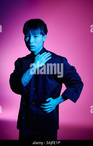 Ein selbstbewusster asiatischer Mann mit stilvoller Kleidung und Tattoos posiert in einer farbenfrohen Umgebung. Stockfoto