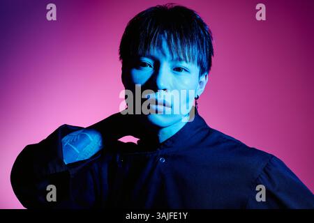 Ein hübscher asiatischer Mann zeigt seinen stilvollen Look mit einem fesselnden Ausdruck in dramatischer Beleuchtung Stockfoto