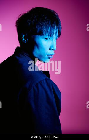 Ein stilvoller junger asiatischer Mann besticht durch seinen Charme in einer lebendigen, farbenfrohen Umgebung. Stockfoto