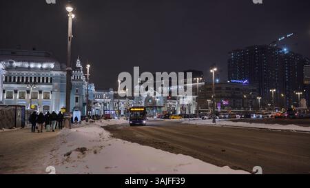 Moskau, Russland - 2. Januar 2025: Blauer Bus fährt nachts auf dem Komsomolskaja-Platz im verschneiten Moskau Stockfoto