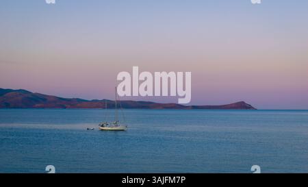 Blick am frühen Morgen auf das Ägäische Meer in Pastellfarben mit weißem Segelboot in der Bucht, Monemvasia, Laconia, Griechenland Stockfoto