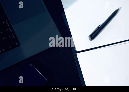 Desktop-Laptop-Smartphone und Papier mit Stift, der auf dem Tisch liegt. Unternehmen, Technologie Stockfoto