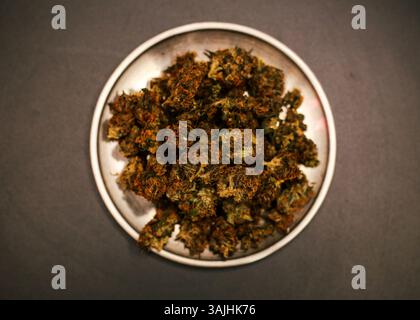 Ein Teller voller Cannabisknospen auf einer schwarzen Oberfläche. Stockfoto