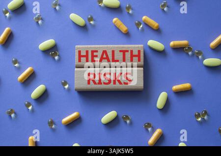 Symbol für Gesundheitsrisiken. Konzeptwort Gesundheitsrisiken auf Holzklötzen. Schöner lila Hintergrund mit Pillen. Medizin und Gesundheitsrisiko-Konzept. Kopierbereich Stockfoto