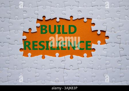 Symbol für Belastbarkeit erstellen. Weißes Puzzle mit Wörtern schafft Widerstandsfähigkeit. Wunderschöner orangefarbener Hintergrund. Business- und Build Resilience-Konzept. Kopierbereich. Stockfoto