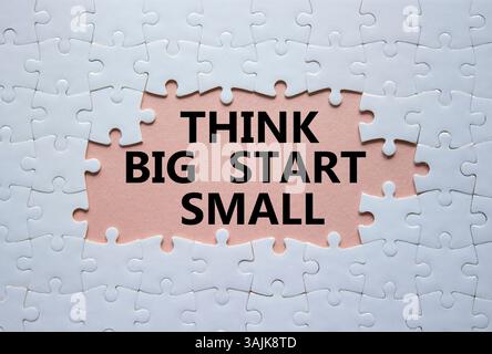 Denken Sie an das große Anfang-kleine Symbol. Konzeptworte denken an großen Anfang klein auf weißem Puzzle. Schöner rosafarbener Hintergrund. Business und Think Big Fang Small Conce Stockfoto