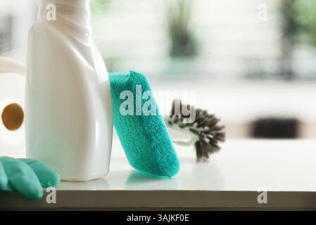 Detail des Desinfektionsmittels und Scheuerschwämme auf Holzschrank mit Schwammhandschuhen und Papier im Badezimmer. Vorderansicht. Stockfoto