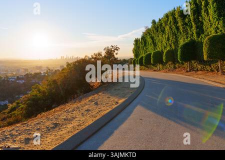 Malerischer Wanderweg im Runyon Canyon Park in Los Angeles, umgeben von üppigem Grün und der Skyline der Stadt, der einen lebhaften Sonnenuntergang mit warmer Beleuchtung einfängt Stockfoto