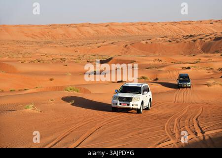RUB Al Khali Wüste, Sultanat Oman - 5. April 2025: Geländewagen fahren in der Wüste Wahiba Sands bei Sonnenuntergang auf der Arabischen Halbinsel Stockfoto