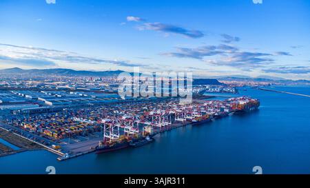 Blick aus der Vogelperspektive auf den Hafen von Barcelona mit Containerschiffen, farbenfrohen Containern und hoch aufragenden Kränen. Stockfoto