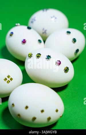 Nahaufnahme glitzernder Eier, die wunderschön auf einer kräftigen grünen Tischoberfläche angeordnet sind, bieten eine frische Interpretation der Urlaubstraditionen. Stockfoto
