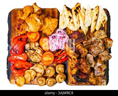 Eine Vielzahl von gegrilltem Fleisch und Gemüse ist kunstvoll auf Holzbrettern angeordnet. Das Aufstrich umfasst Hühnchen, Lamm, Paprika und Zwiebeln, wobei VI Stockfoto