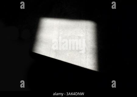 Sonnenlicht fällt durch das Fenster auf die schwarze Wand Stockfoto