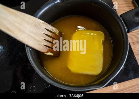 Schmelzender Butterwürfel in einer heißen Pfanne, um Schokoladenglasur zu machen Stockfoto