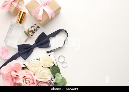 Elegante Hochzeitszubehör für den Bräutigam – Parfüm, Fliege, Boutonniere und Hochzeitsringe auf hellem Hintergrund. Hochwertige Fotos Stockfoto