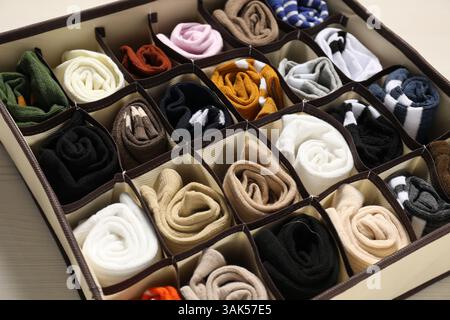 Organizer mit verschiedenen Socken auf hellem Holztisch, Großaufnahme Stockfoto