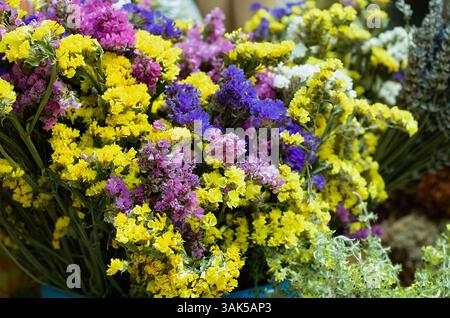 Nahaufnahme eines lebhaften Blumenstraußes mit getrockneten Blüten in Gelb-, Violett- und Rosa-Tönen. Perfekt für Themen wie Blumenschmuck, Dekoration, natürliche Schönheit, Stockfoto