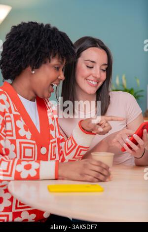 Afroamerikanische und kaukasische Freunde lächeln, während sie gemeinsam auf das Smartphone schauen Stockfoto