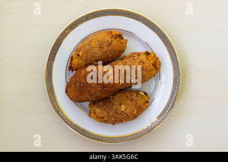 Leckeres hausgemachtes Dimer-Häckseln auf einer Keramikplatte auf einer hellen Holzoberfläche. Dieses köstliche Gericht, auch bekannt als Eierkotelett oder Dimer-Alur-Kotelett, ist sehr beliebt Stockfoto