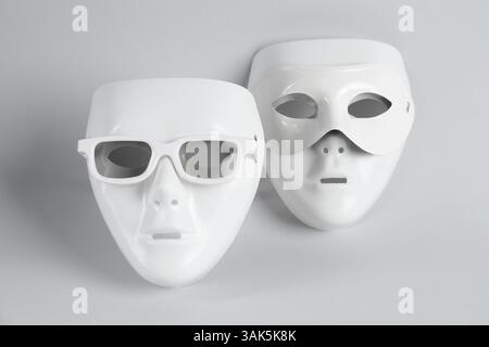 Theatermasken aus Plastik mit Sonnenbrille auf hellgrauem Hintergrund Stockfoto