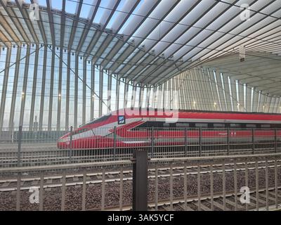 Reggio Emilia, Italien - 11. April 2025: Ein roter elektrischer Hochgeschwindigkeitszug, Frecciarossa von Trenitalia, parkt an einem Bahnsteig im Bahnhof Mediopadana Stockfoto