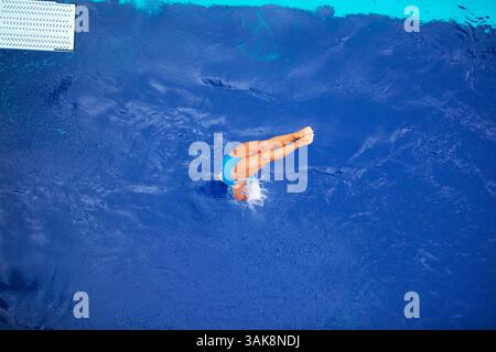 Frau taucht vom Sprungbrett in den Swimmingpool Stockfoto