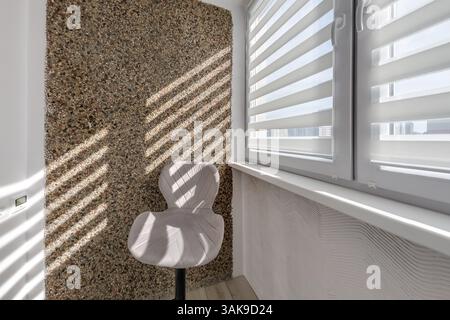 Moderne Zebrajalousien mit doppelten Rollläden an großen Fenstern in heller minimalistischer Innenausstattung mit Sonnenlicht auf dem Balkon Stockfoto