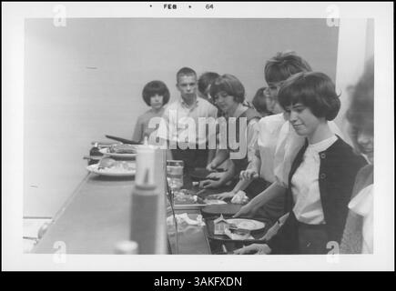 Das Schulmittagsprogramm 1964 bot den Schülern ausgewogene und nahrhafte Mahlzeiten. Jährlich wurden über sechs Millionen Kartons Milch und mehr als anderthalb Teller Mittagessen zubereitet und serviert. Das Foto mit dem Stempel Februar 1964 ist Teil des Jahresberichts 1963, das eine Gruppe in einem Innenraum zeigt. Stockfoto