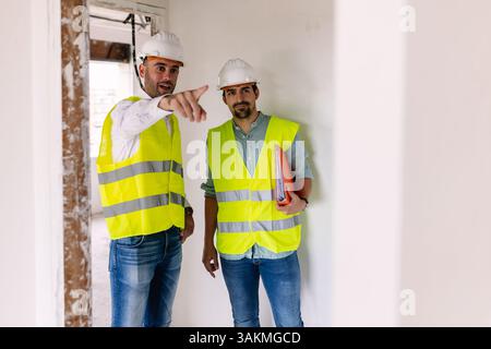 Ingenieure besprechen Blueprint mit Sicherheitsweste und Helm auf der Baustelle Stockfoto