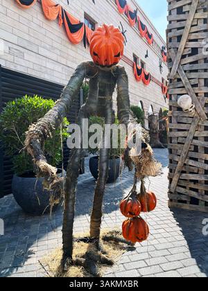 Eine Halloween-Straßendekoration mit einer gruseligen Vogelscheuche und einem großen Kürbiskopf mit kleinen Jack-o-Laternen. Stockfoto