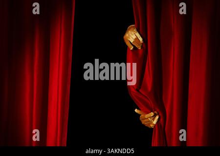 Weibliche Hände in Handschuhen öffnen rote Vorhänge auf schwarzem Hintergrund Stockfoto