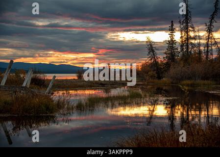 Wunderschöner Sonnenuntergang in Kanada im Herbst mit leuchtend rosa, schrägen Wolken, die sich über einer nördlichen Landschaft bilden. Offener See mit Sonnenuntergang Stockfoto