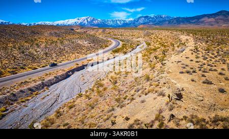 Luftaufnahme der Desert Road mit Black Car und schneebedeckten Bergen Stockfoto