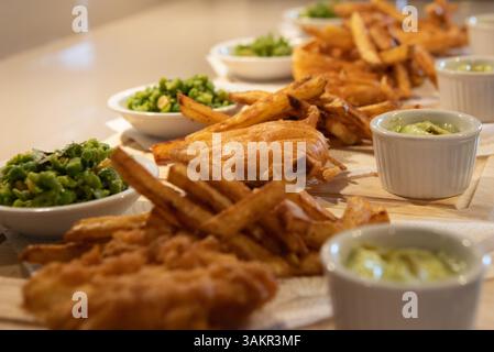 Fish & Chips Mahlzeit mit Erbsen auf Holzplatte. Leckeres Essen Abendessen, Meeresfrüchte. Stockfoto