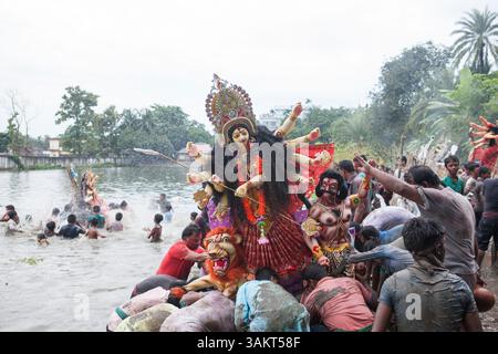 Gläubige tauchen während des letzten Ritual von Durga Puja ein Durga-Idol ins Wasser ein und symbolisieren die Rückkehr der Göttin zu ihrem himmlischen Wohnort. Stockfoto