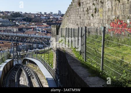 Blick auf die Gleise der Standseilbahn Funicular dos Guindais und die Brücke Ponte Luis (Luiz) I., auf der rechten Stadtmauer Muralha Fernandina, in Stockfoto