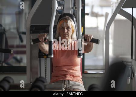 Eine ältere Frau übt Übungen auf einem Fitness-Trainer Stockfoto