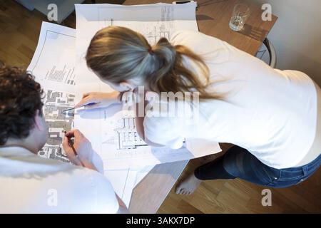 Hochwinkelaufnahme männlicher und weiblicher Architekten bei der Arbeit. Frau, die auf den Ort auf der Karte zeigt Stockfoto