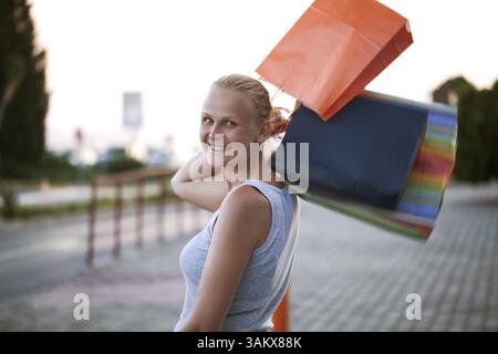 Glückliche junge Frau outdoor werfen Taschen auf die Schulter. Zufriedenheit mit guten Einkaufsmöglichkeiten Stockfoto