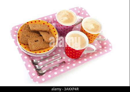 Sprenkel Tassen und Untertassen mit Keksen isoliert über weiß Stockfoto