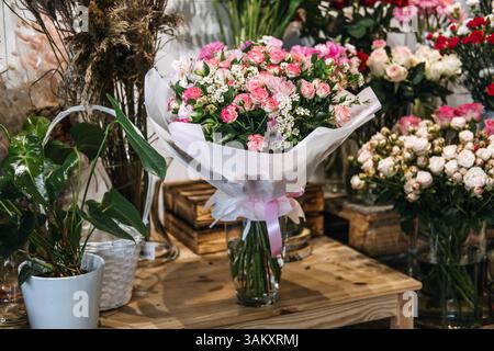 Blumenstrauß aus rosa und weißen Blumen, in Tücher und Band gewickelt, in einem Blumengeschäft ausgestellt. Florales Business Marketing, romantisches Geschenk, klein Stockfoto