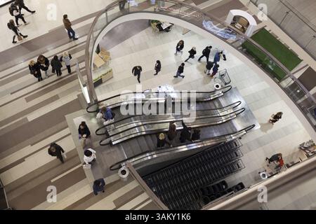 Hochwinkelaufnahme von Personen, die in einem modernen Handelszentrum herumlaufen und eine Rolltreppe fahren Stockfoto