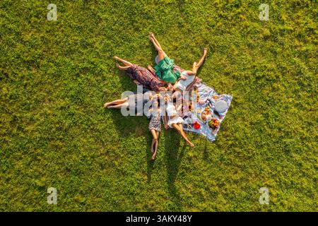 Aus der Vogelperspektive mit einer Gruppe von Frauen, die sich in der Natur bei einem Picknick am Abend entspannen. Stockfoto